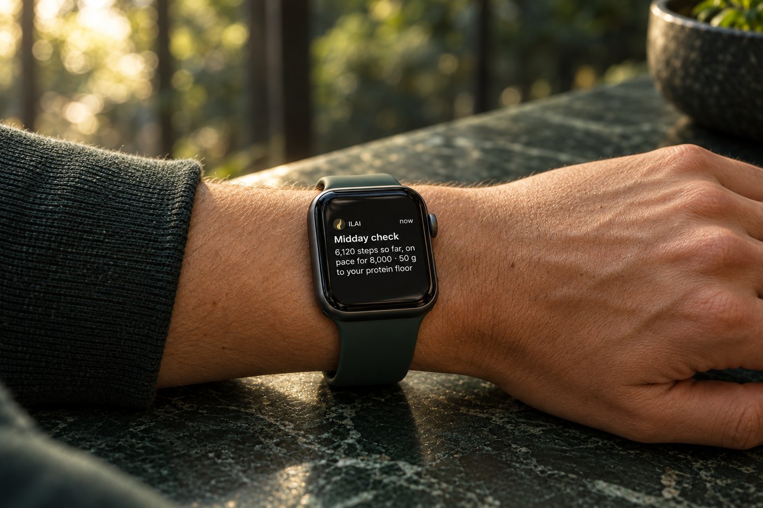 An Apple Watch on a wrist on green marble showing an ILAI notification: “Midday check. 6,120 steps so far, on pace for 8,000 · 50 g to your protein floor”